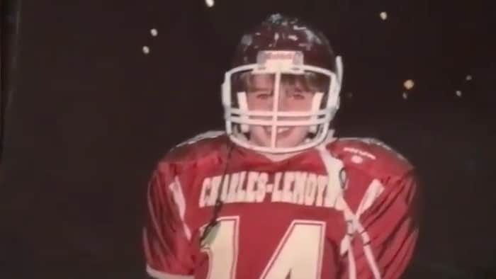 Il porte l'uniforme de l'équipe et regarde la caméra en souriant.