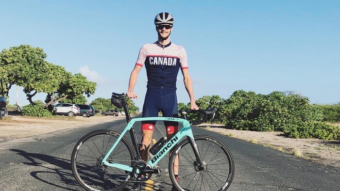 Un triathlète pose devant son vélo.