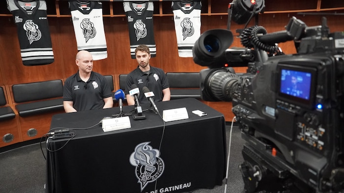 Deux hommes de hockey discutent avec les journalistes lors d'une conférence de presse.