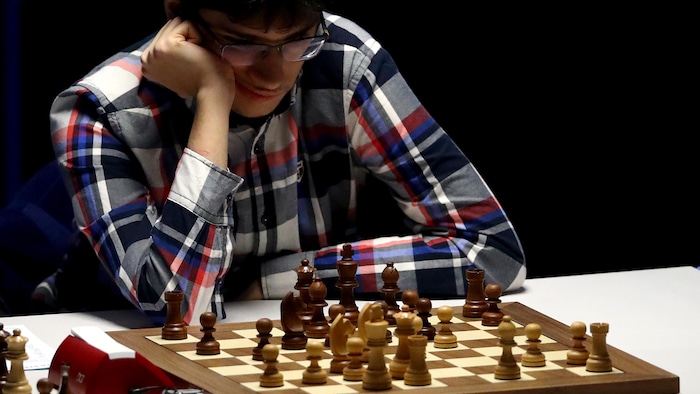 Un homme regarde intensément un plateau d'échecs.