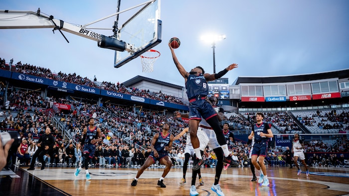 Un joueur de basket monte au panier. 