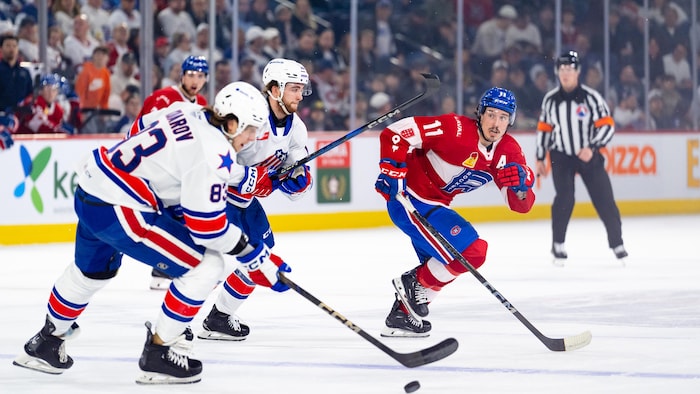 Un joueur du Rocket tente de rejoindre deux adversaires sur la glace. 