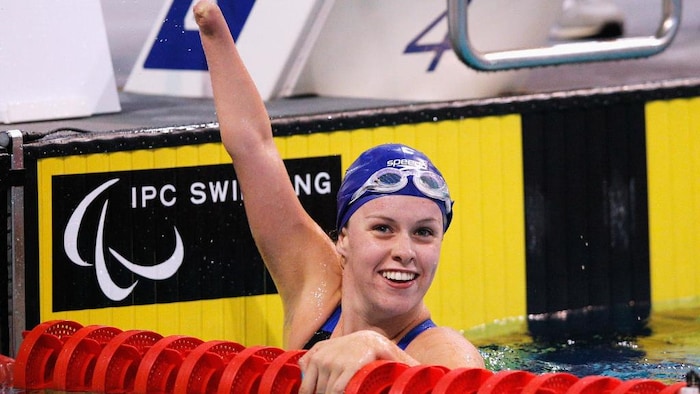 Amy Marren célèbre en soulevant son bras amputé, dans la piscine, après une victoire.