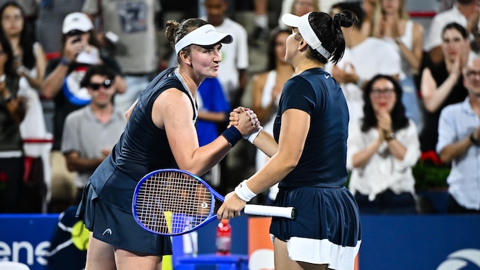 Deux joueuses de tennis se serrent la main au filet. 
