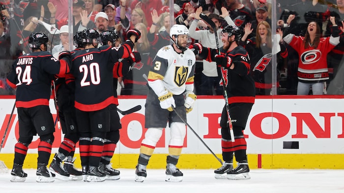 Des hockeyeurs célèbrent un but près d'un adversaire.