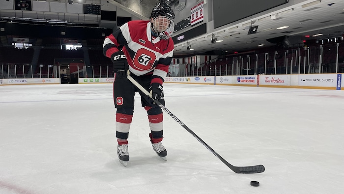 Un patineur s'élance avec la rondelle sur une patinoire.