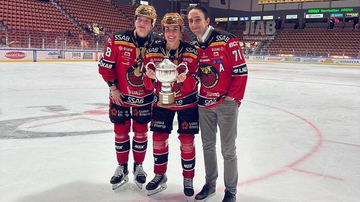 Des joueuses de hockey posent avec un trophée.