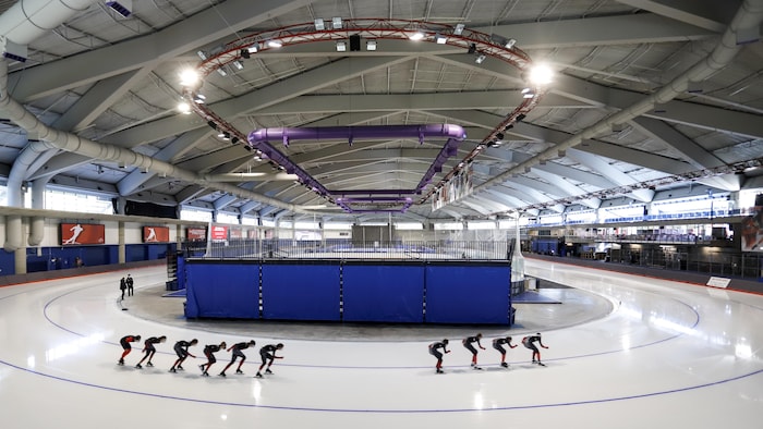 Des patineurs de vitesse se suivent en file.