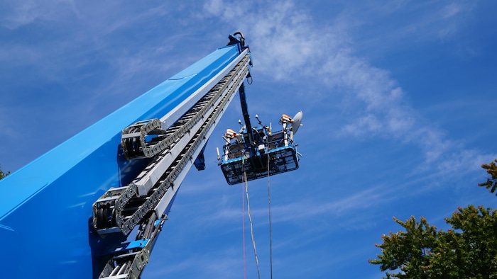 Une antenne est soulevée par une grue.
