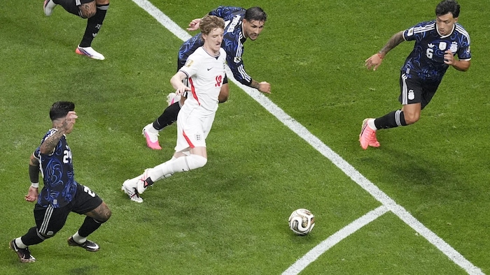 Il fonce vers le ballon, entouré de rivaux.