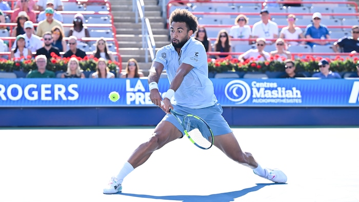 Un joueur de tennis frappe un revers. 