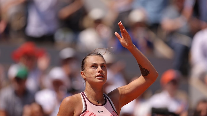 Une joueuse de tennis fait un geste de la main en regardant la foule.