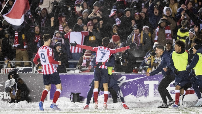 Un joueur de soccer saute dans les bras de son coéquipier, les bras écartés, après avoir marqué le but de la victoire en prolongation.
