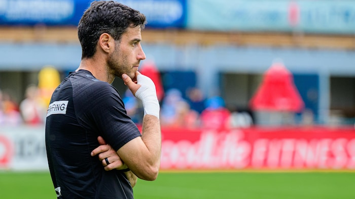 Un entraîneur de soccer regarde ses joueurs à l'œuvre pendant un match professionnel.