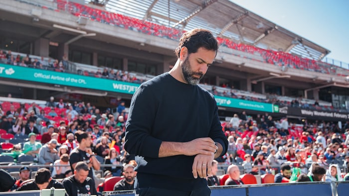 Un entraîneur de soccer regarde sa montre pendant une partie professionnelle.