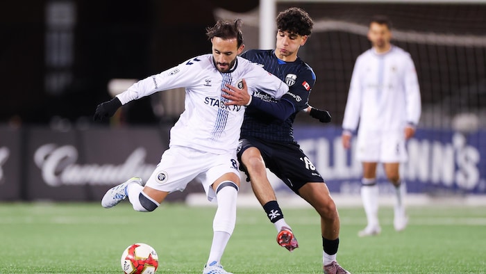 Deux joueurs de soccer professionnels se battent pour la possession du ballon.