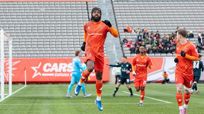 Un joueur de soccer saute dans les airs pour célébrer un but.