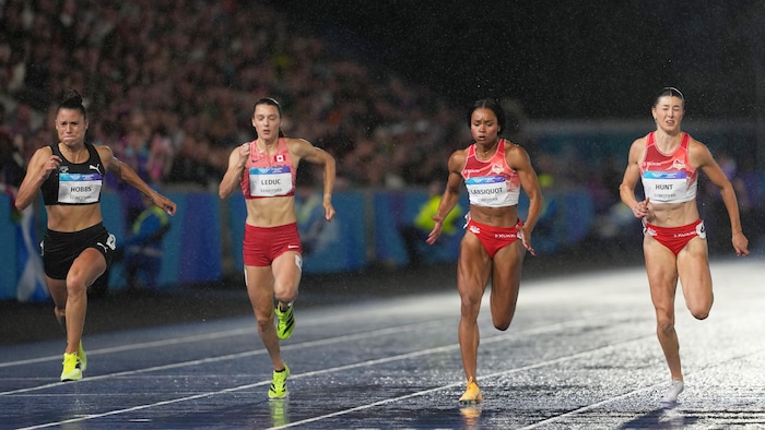 Quatre sprinteuses courent sous la pluie. 
