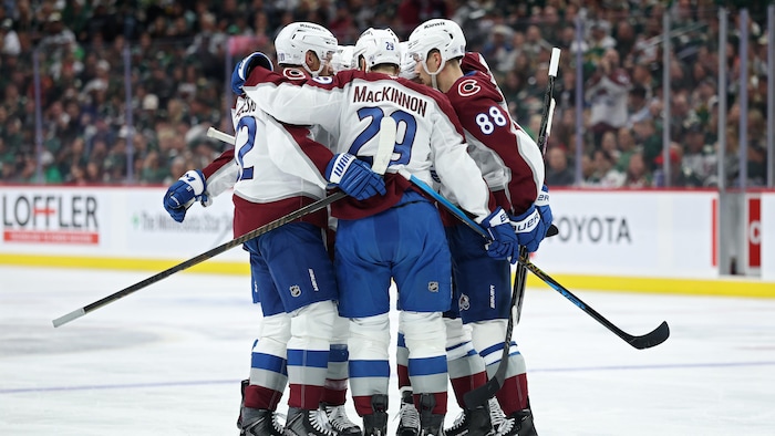 Des joueurs d'une équipe se font l'accolade sur la glace.