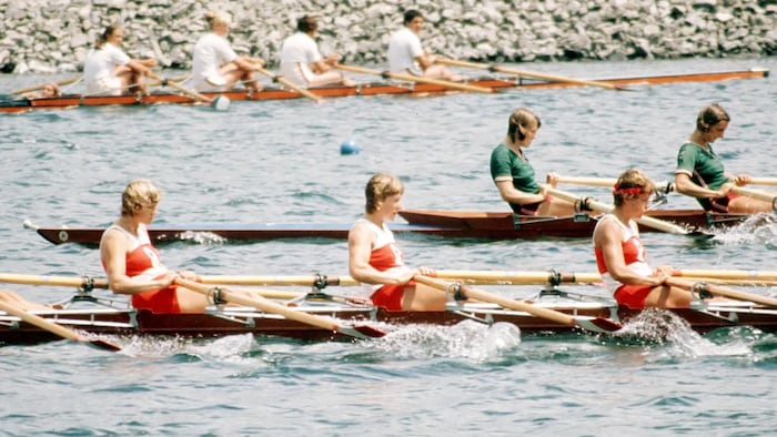 Trois rameuses canadiennes participent à une épreuve olympique d'aviron.