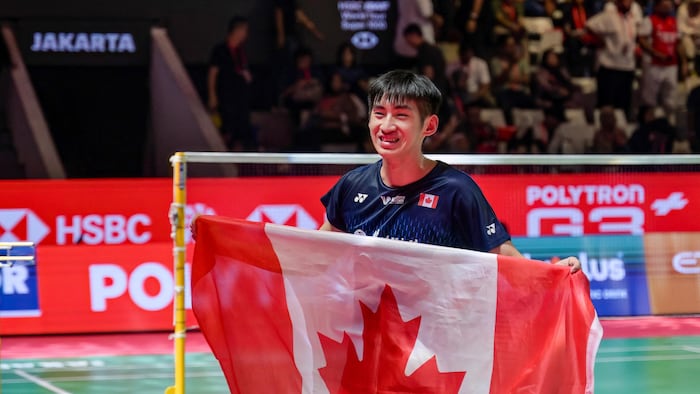 Il pose pour une photo avec le drapeau du Canada.