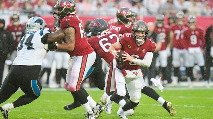 A football player runs with the ball next to a scrum.