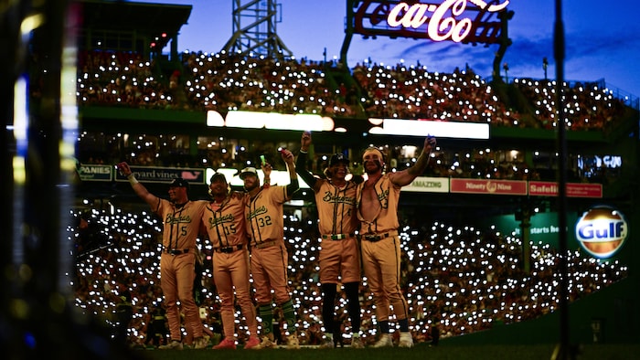 Des joueurs de baseball en jaune salue la foule.