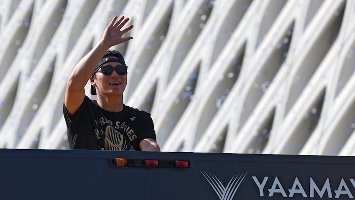 À bord d'un autobus, Yoshinobu Yamamoto salue la foule.