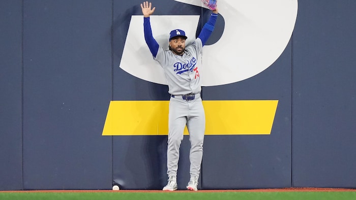 Un joueur des Dodgers de Los Angeles lève les bras alors que la balle est logée sous le coussin de la clôture.