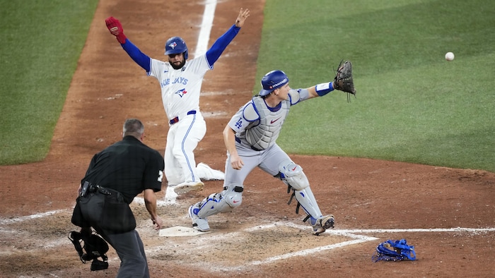 Un joueur des Blue Jays de Toronto glisse vers le marbre alors que le receveur des Dodgers de Los Angeles s'apprête à attraper la balle.