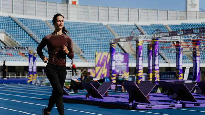Une femme court sur une piste d'athlétisme.