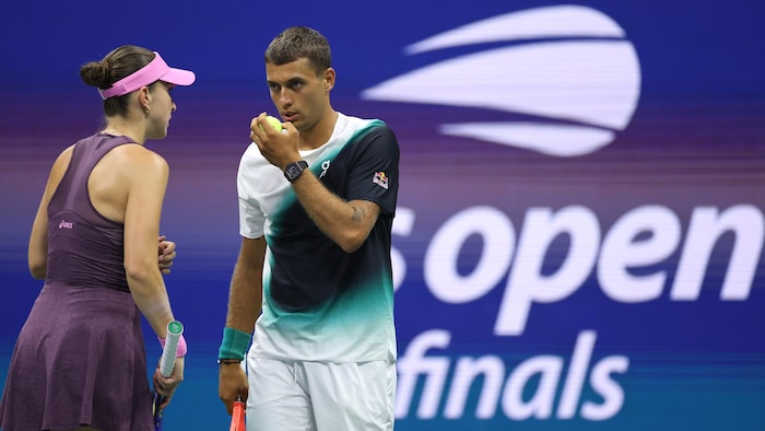 Deux joueurs de tennis se consultent sur le terrain.