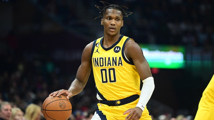 Il drible le ballon avec les cheveux au vent. 