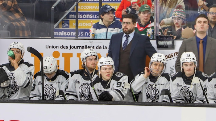 Un entraîneur de hockey regarde l'Action pendant une rencontre.
