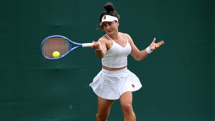 Une joueuse de tennis frappe une balle en coup droit.