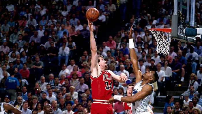Un joueur de basketball lance un tir au-dessus d'un défenseur.