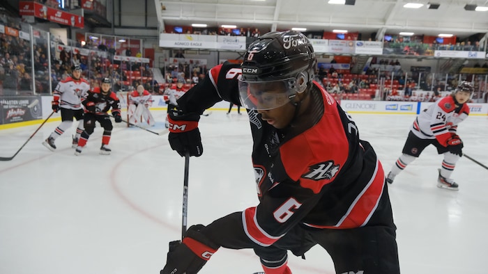 Le hockeyeur récupère une rondelle dans le coin de la patinoire.