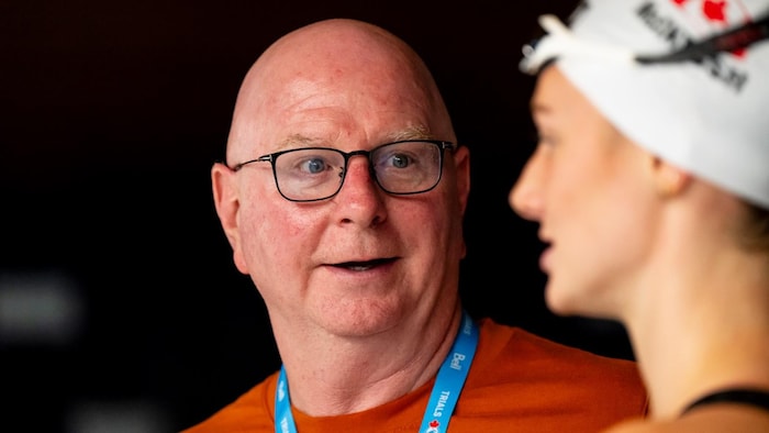 Un entraîneur de natation regarde sa protégée.