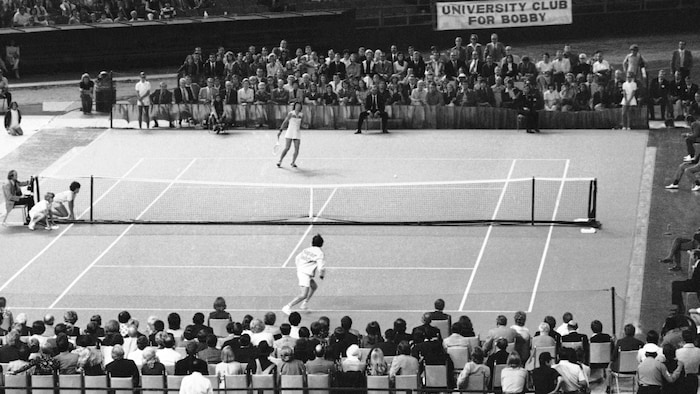 Un homme et une femme disputent un match de tennis devant une foule.