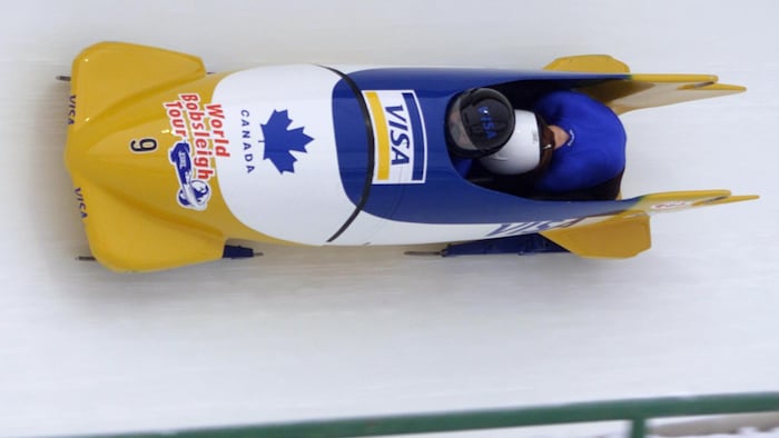 Deux femmes conduisent un bobsleigh dans une courbe glacée.