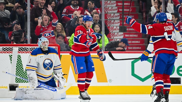 Deux joueurs célèbrent un but devant un gardien.