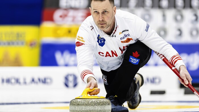 Le joueur de curling s'apprête à lancer une pierre.