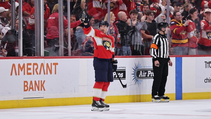 Un joueur de hockey le bras dans les airs, pointe la foule. 