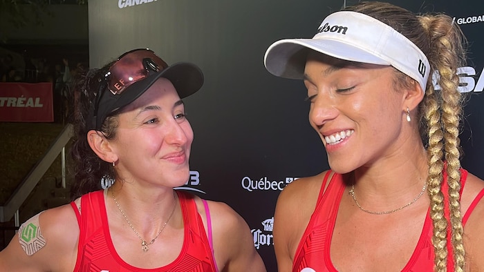 Deux femmes sourient en répondant à des questions devant un micro de Radio-Canada.