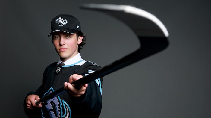 Un joueur de hockey pose à la caméra avec son bâton de hockey.
