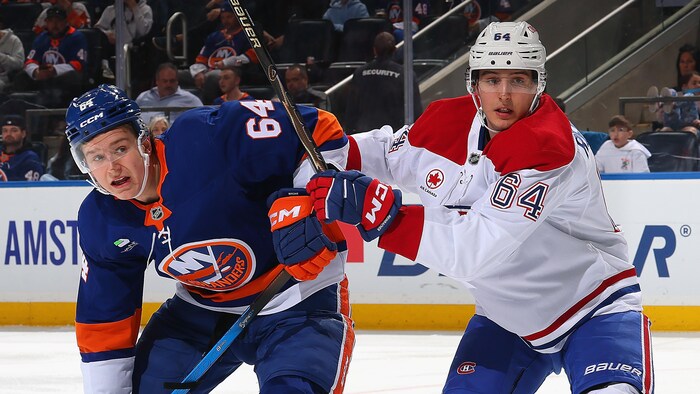 Un hockeyeur repousse un rival à deux mains.