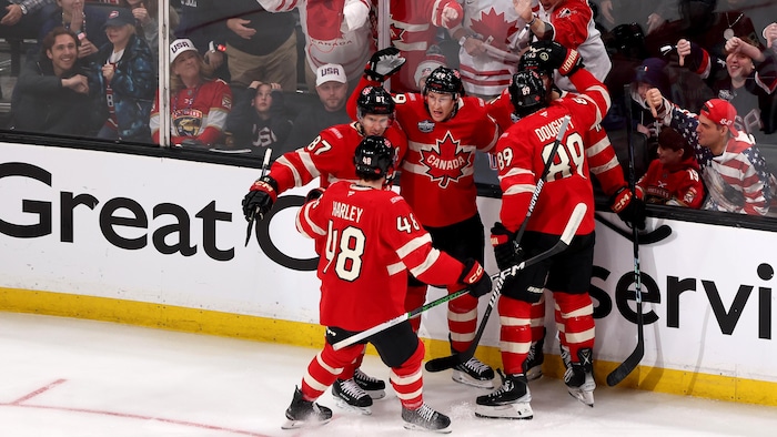 Des joueurs de hockey célèbrent sur la glace, devant des spectateurs. 