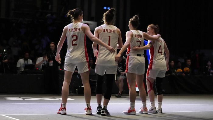 Les joueuses de l'équipe canadienne Katherine et Michelle Plouffe, Paige Crozon et Kacie Bosch s'enlacent avant le début d'un match.