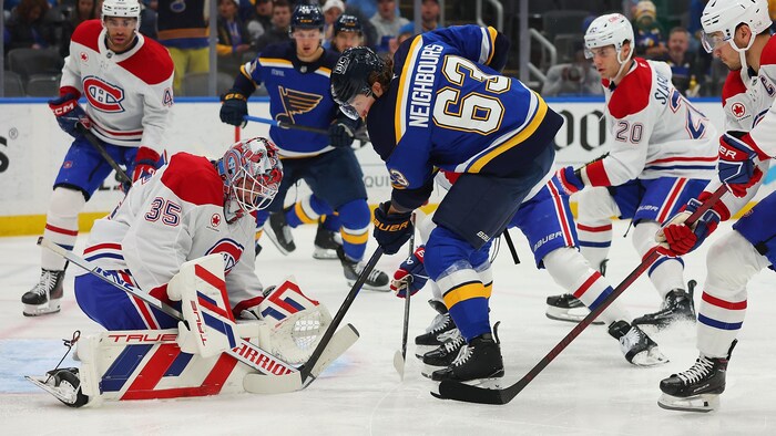 Un gardien de but fait un arrêt devant un joueur. 