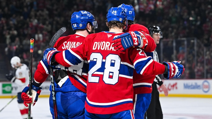 Trois joueurs de hockey célèbrent un but. 